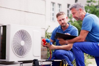 ac-installation-in-claremont-ca HVAC technicians reviewing an outdoor air conditioning unit in Broomfield, CO